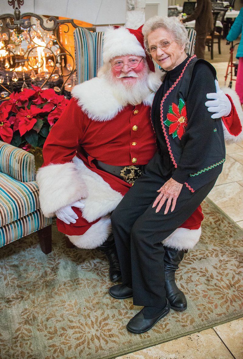 Rick Sublett of Conway, aka Santa Rick, takes a picture with Sue Lynn on his lap at The Manor assisted-living community in Little Rock. Sublett has been making appearances as Santa for about 10 years, to the young and young at heart.