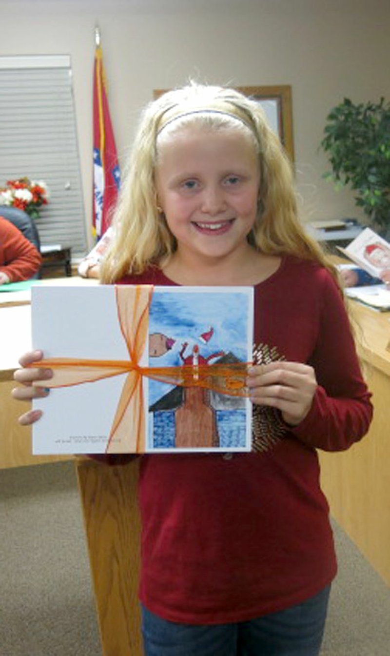 Westside Eagle Observer/SUSAN HOLLAND Piper Batie, a fourth grader at Gravette Upper Elementary School, displays the Christmas card she designed for the Gravette School District's annual contest. Piper was present at the Dec. 18 meeting of the Gravette School Board and led the Pledge of Allegiance to open the meeting. She was given a packet of cards with designs by winners at each school.