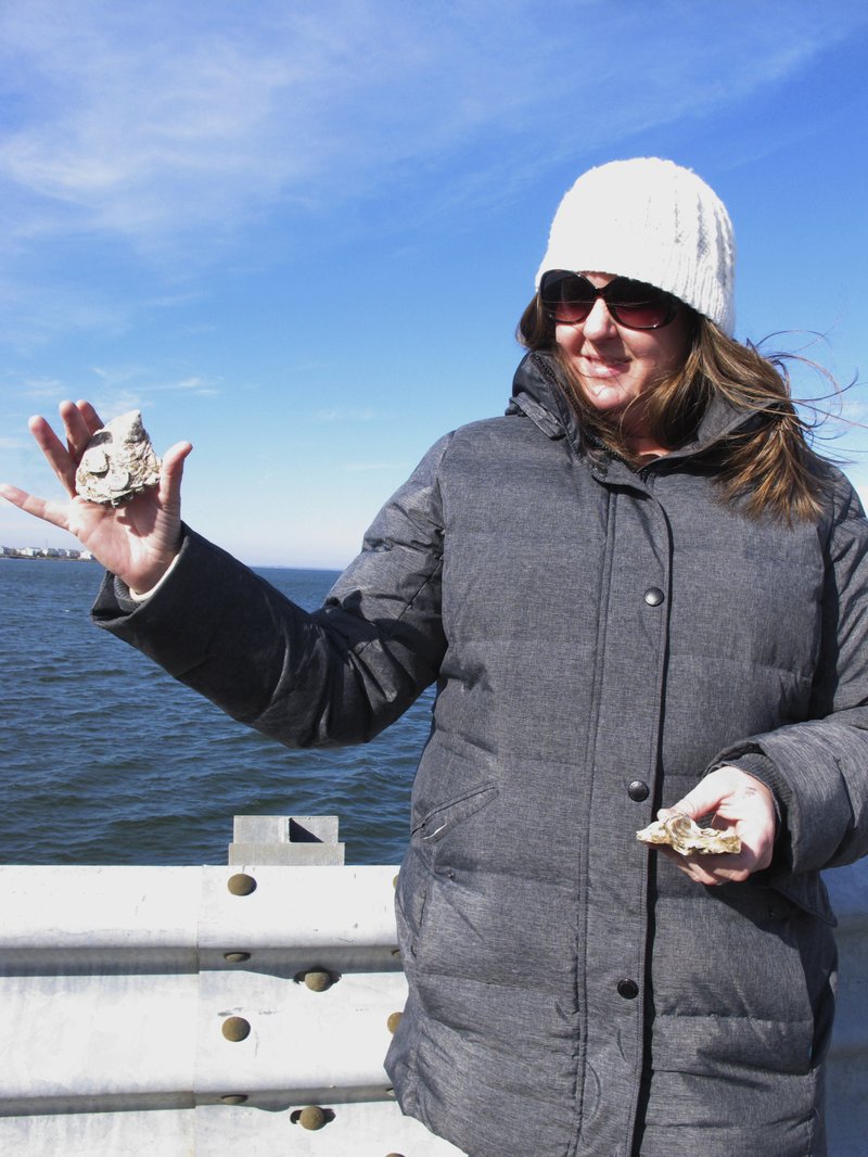 In this Nov. 21, 2017 photo, Meredith Comi of the NY/NJ Baykeeper environmental group holds oyster shells that are used in a project to protect the shoreline of the Earle Naval Weapons Station in Middletown N.J. Coastal communities around the world are planting oyster reefs to protect shorelines against the damaging effects of waves during storms, including the Navy pier that suffered $50 million worth of damage during Superstorm Sandy in 2012. (AP Photo/Wayne Parry)