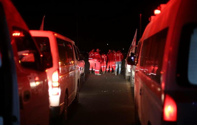 In this photo released by the Syrian official news agency SANA, members of the Syrian Arab Red Crescent gather near their ambulances during a human evacuation of sick people from the eastern Ghouta, near Damascus, Syria, Wednesday, Dec. 27, 2017. 