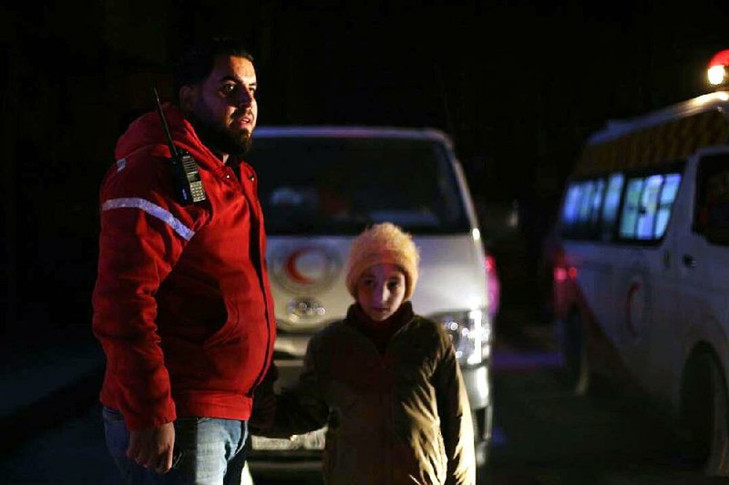 A member of the Syrian Arab Red Crescent helps a child during a roundup of sick people in eastern Ghouta, near Damascus, in this photo released by the official Syrian Arab News Agency.