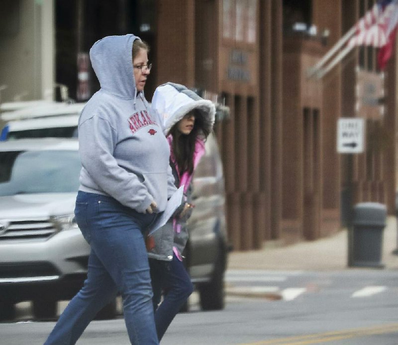 Pedestrians brave the chilly wind Tuesday afternoon while crossing a street in downtown Little Rock. Temperatures in central Arkansas hovered in the upper 30s the day after Christmas, with lows overnight expected to plunge into the upper 20s.