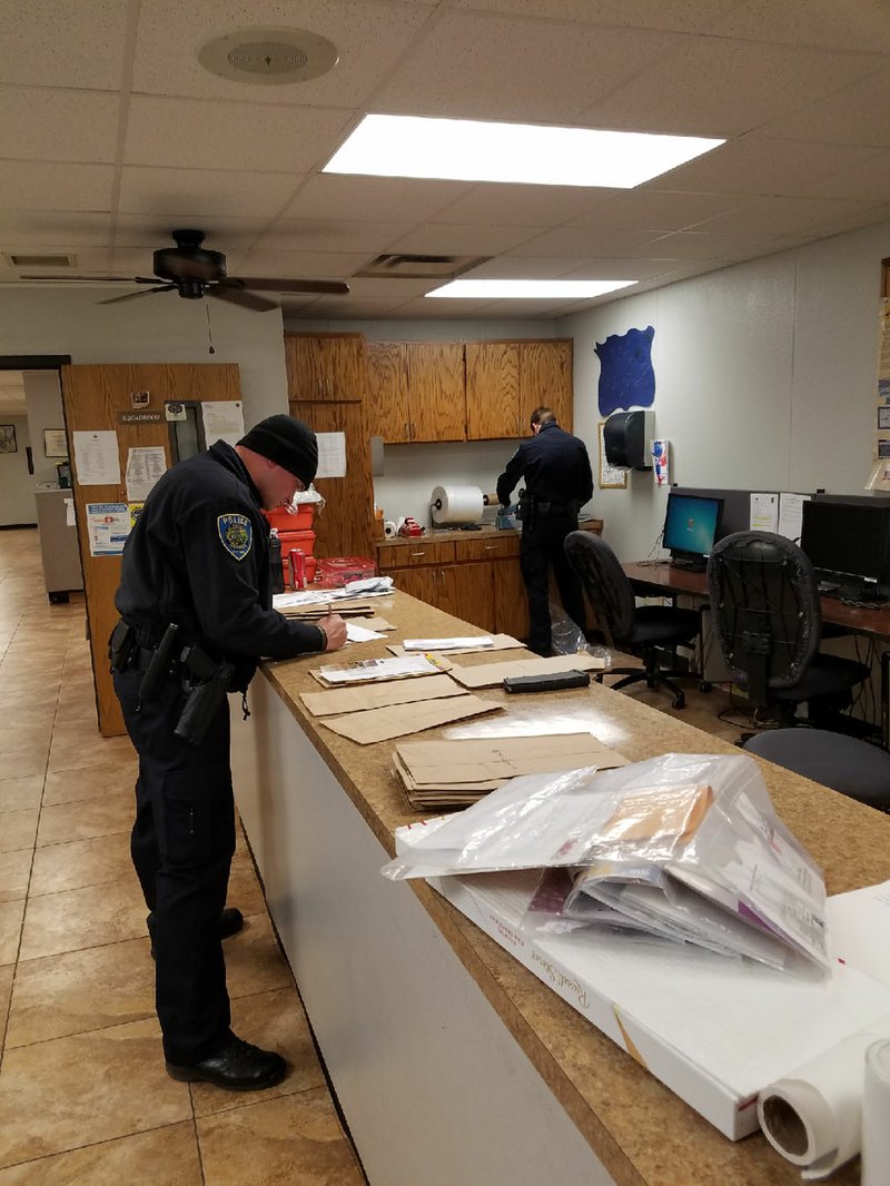 NWA Democrat-Gazette/ASHTON ELY Cpl. Marcus Peace and Officer Seay Floyd work to sort through some of the mail that was scattered during Tuesday night's mail thefts across east Fayetteville.