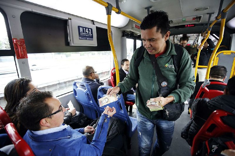 Venezuelan Jorge Gutierrez hawks a 100-bolivar bill to a passenger on a bus in Bogota, Colombia, in mid-December. Gutierrez says he can earn roughly $20 in a day selling the virtually worthless currency. 