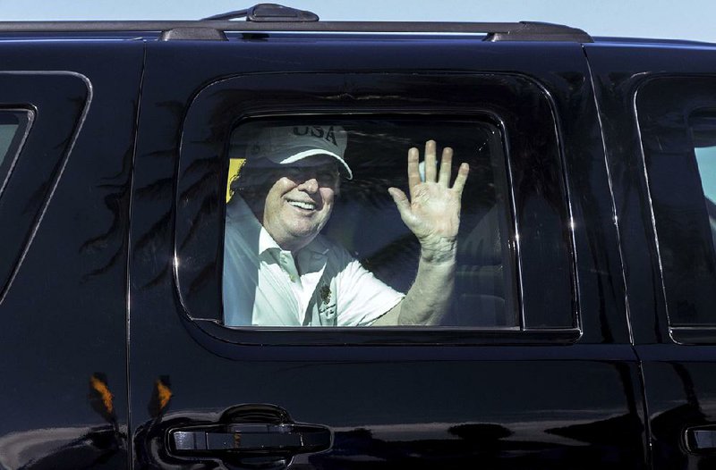 President Donald Trump waves to supporters Thursday as his motorcade travels along Southern Boulevard in West Palm Beach, Fla., to his Mar-a-Lago estate from Trump International Golf Club. 