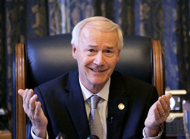 Gov. Asa Hutchinson talks with reporters at the state capitol in Little Rock.