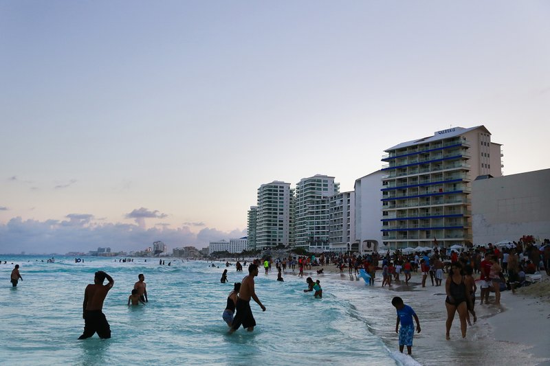 Beachgoers wade on the beach in Cancun, Mexico, on April 4, 2015. 
