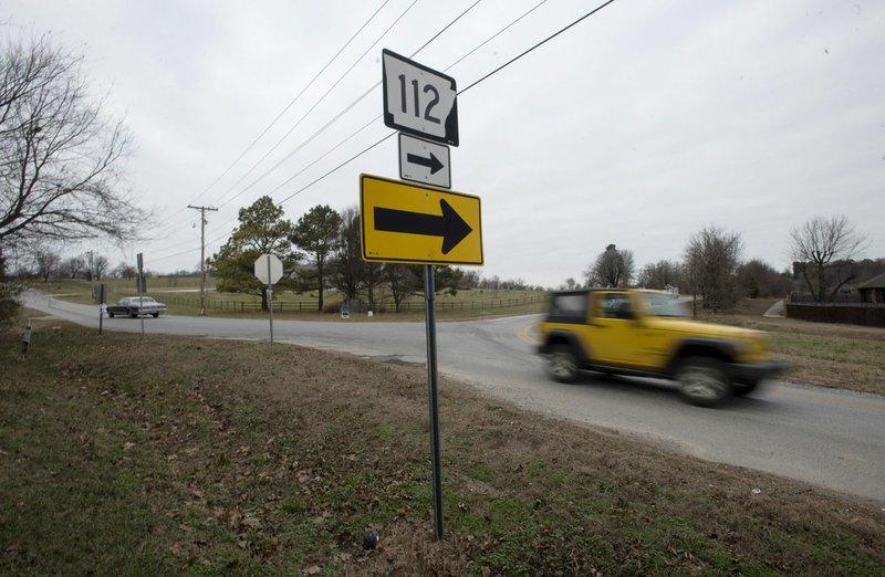 NWA Democrat-Gazette/CHARLIE KAIJO Cars pass by Thursday on the corner of Arkansas 112 and Howard Nickell Road in Fayetteville. The city is considering partnering with Washington County to to improve the intersection.