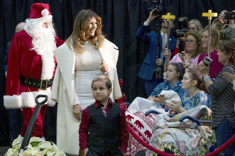 First lady Melania Trump often wears her overcoat draped over her shoulders, as she did in this appearance with Santa Claus at the Children’s National Medical Center in Washington. 