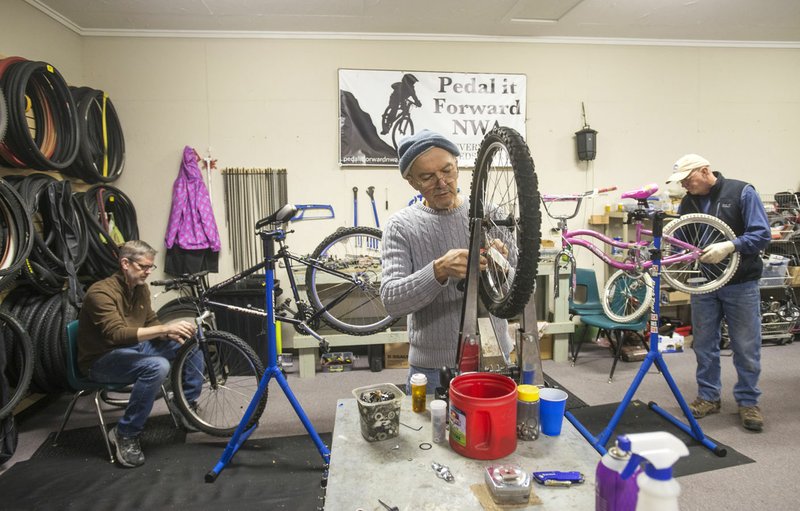 NWA Democrat-Gazette/BEN GOFF &#8226; @NWABENGOFF David Tovey (from left) of Rogers, founder of Pedal it Forward NWA, Steve Marquess, a volunteer from Bentonville, and Tim Garton, a volunteer from Bella Vista, tune up and repair bicycles Dec. 26 at Pedal it Forward NWA in Bentonville.