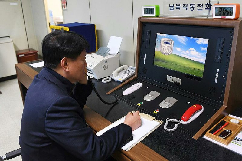 A South Korean government official talks with a North Korean officer Wednesday during a call on the dedicated hotline at the South Korean village of Panmunjom. North Korean leader Kim Jong Un reopened the communication channel on Wednesday.  