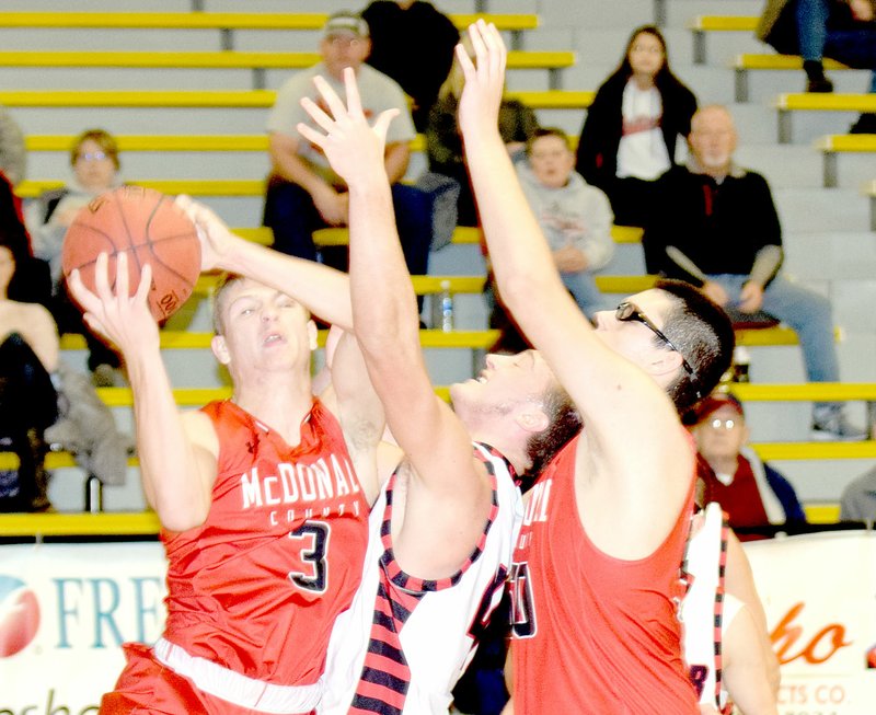 RICK PECK/SPECIAL TO MCDONALD COUNTY PRESS McDonald County's Peyton Barton grabs a rebound away from Lamar's Travis Bailey as Tim Shields puts Bailey in a Mustang vice during McDonald County's 64-57 win on Dec. 30 in the 13th-place game of the 63rd Neosho Holiday Classic.