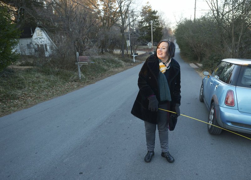 NWA Democrat-Gazette/ANDY SHUPE Sarah Marsh, Fayetteville City Council member, uses a tape measure Wednesday to measure the width of Oliver Avenue in Fayetteville to better understand options to improve the street and make it more walkable.