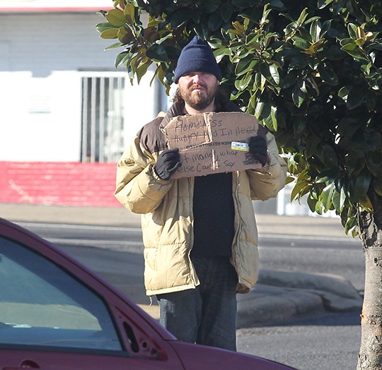 The Sentinel-Record/Richard Rasmussen IN ABEYANCE: A man panhandles near the corner of Grand and Central avenues Thursday as the city ordinance prohibiting the interaction of motorists and pedestrians in public rights of way took effect. The city said it isn't likely to enforce the ordinance until a federal court rules on its constitutionality.