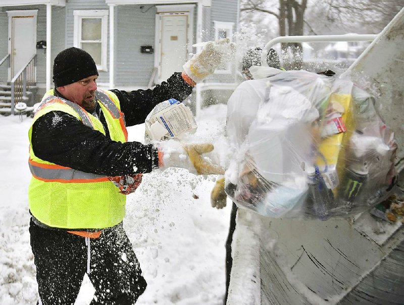 Sanitation worker Paul Fairbanks collects garbage in the snow and cold Friday in Syracuse, N.Y., as wind chills plunged as low as minus 25 degrees. 
