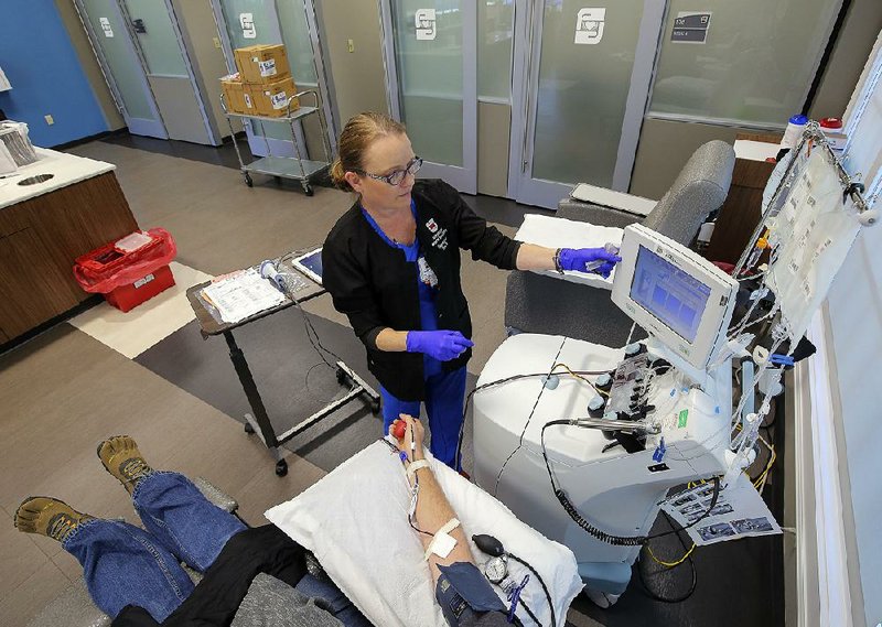 Tina Bell prepares equipment to draw platelets and plasma from donor Tony Calkins of Conway on Thursday at the Arkansas Blood Institute’s Little Rock location. 