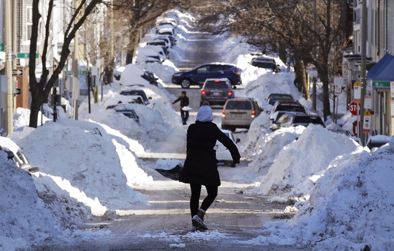 Mollie Lane carries a shovel-full of snow down the street to a pile while digging her car out in the South Boston neighborhood of Boston, Friday, Jan. 5, 2018. Frigid temperatures, some that could feel as cold as minus 30 degrees, moved across the East Coast on Friday as the region attempted to clean up from a massive winter storm. (AP Photo/Charles Krupa)
