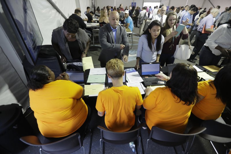 FILE - In this Wednesday, Aug. 2, 2017, file photo, job candidates are processed during a job fair at the Amazon fulfillment center in Robbinsville Township, N.J. On Friday, Jan. 5, 2018, the U.S. government issues the December jobs report. (AP Photo/Julio Cortez, File)