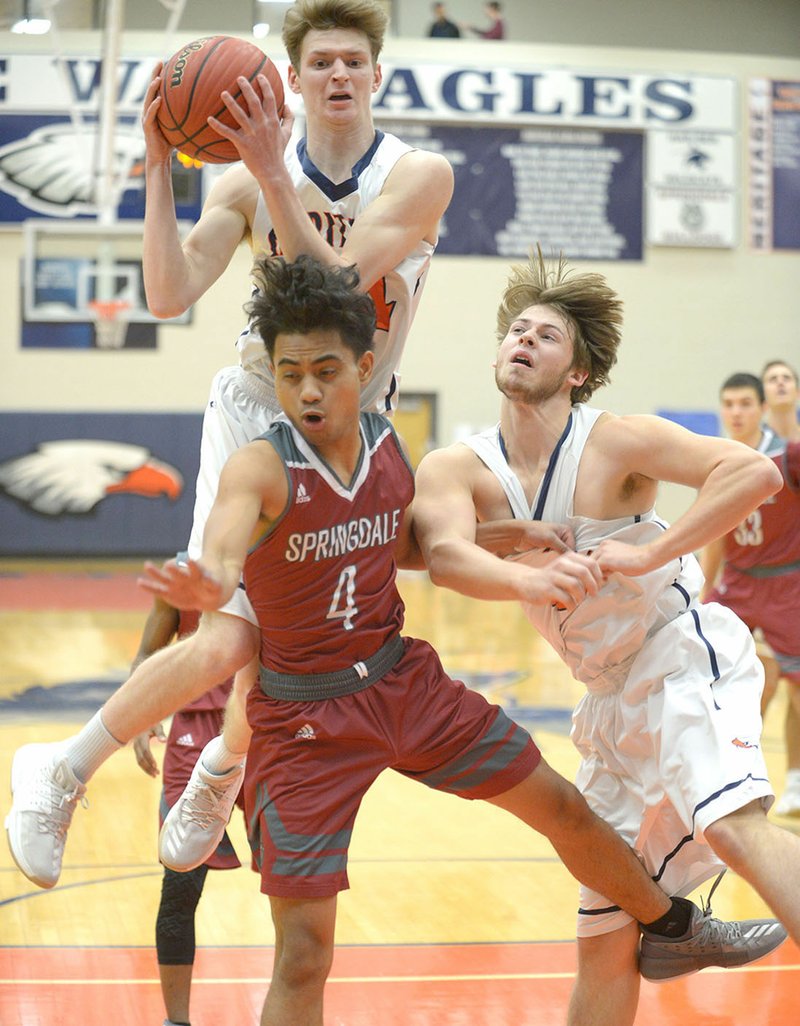 Rogers Heritage’s Bryce Breedlove (top) pulls down a rebound over Springdale High’s Joe Jibke (4) as Heritage’s Brennan Fincher (right) blocks out Friday in Rogers.