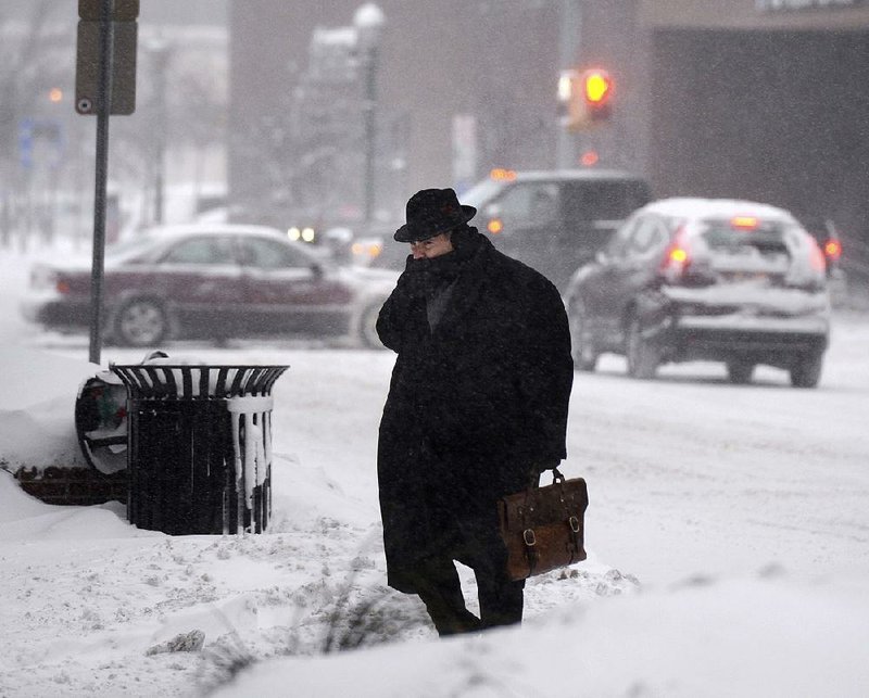 A man crosses a snow-covered street Friday in downtown Syracuse, N.Y. 