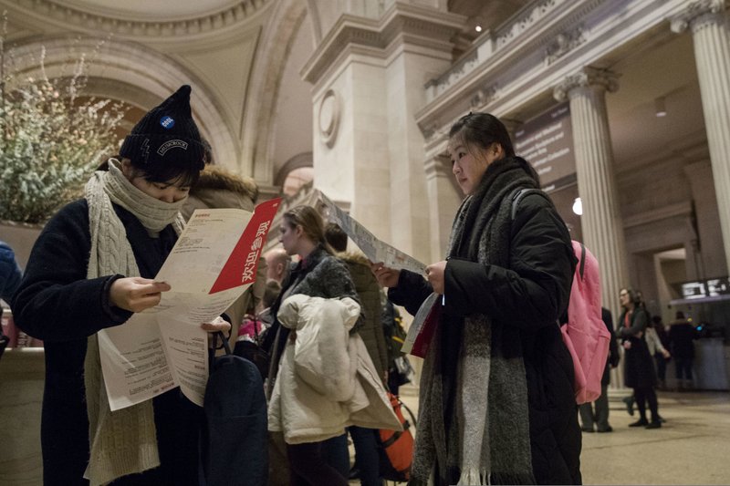 Visitors to the Metropolitan Museum of Art inspect the map of the museum after purchasing a ticket, Thursday, Jan. 4, 2018, in New York. Starting March 1, the museum will charge a mandatory $25 entrance fee to most adult visitors who don't live in New York state, the Met's president and CEO, Daniel Weiss, announced Thursday. Admission will still be pay-what-you-wish for New Yorkers. (AP Photo/Mary Altaffer)