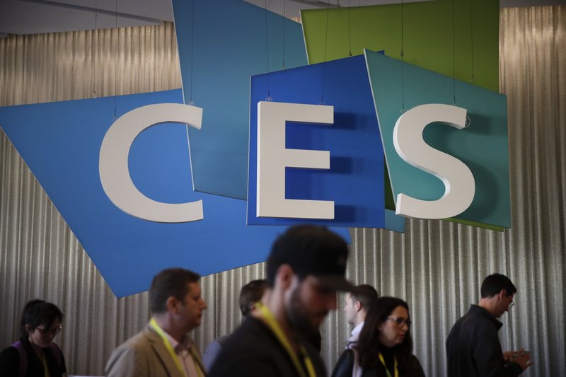 FILE - In this Friday, Jan. 6, 2017, file photo, show attendees walk past the CES sign at CES International in Las Vegas. As the 2018 CES gadget show kicks off in Las Vegas, manufacturers are expected to unveil new ways for consumers to control their products with voice commands over smart speakers such as Amazon Echo. (AP Photo/Jae C. Hong, File)