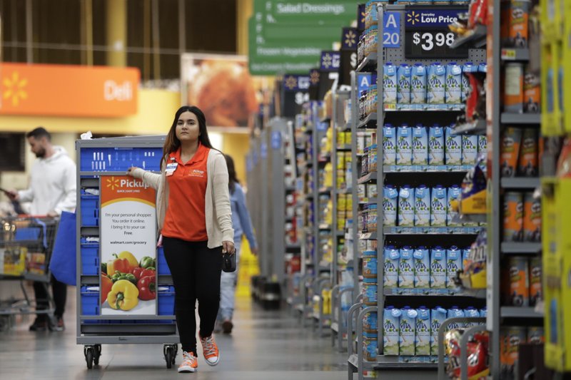 In this Thursday, Nov. 9, 2017, photo, Laila Ummelaila, a personal shopper at the Walmart store in Old Bridge, N.J., pulls a cart with bins as she shops for online shoppers. Personal shoppers collect items on online orders and greet customers at a pickup location in the parking lot. (AP Photo/Julio Cortez)