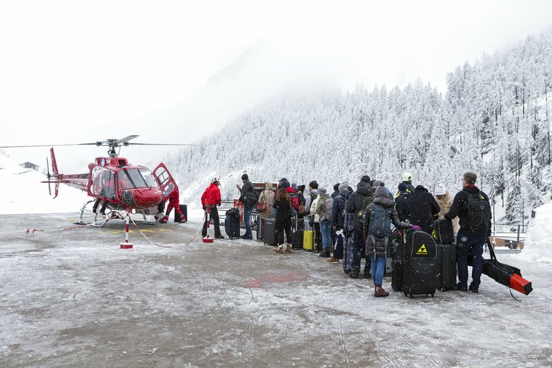 Tourists wait in line at the heliport of Air Zermatt for a flight by airlift into the valley to Raron, in Zermatt, on Tuesday, Jan. 9, 2018.
