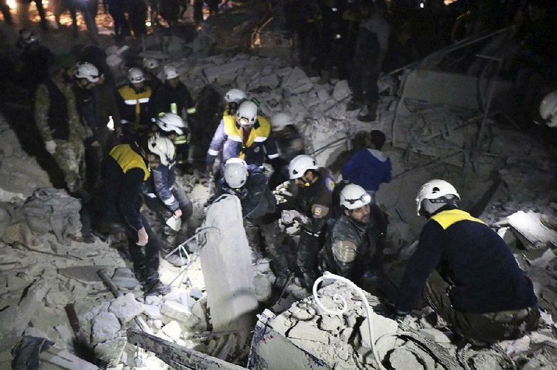 Syrian rescuers search the damaged office of militant group Ajnad al-Koukaz in Idlib, Syria, after it was bombed Sunday.
