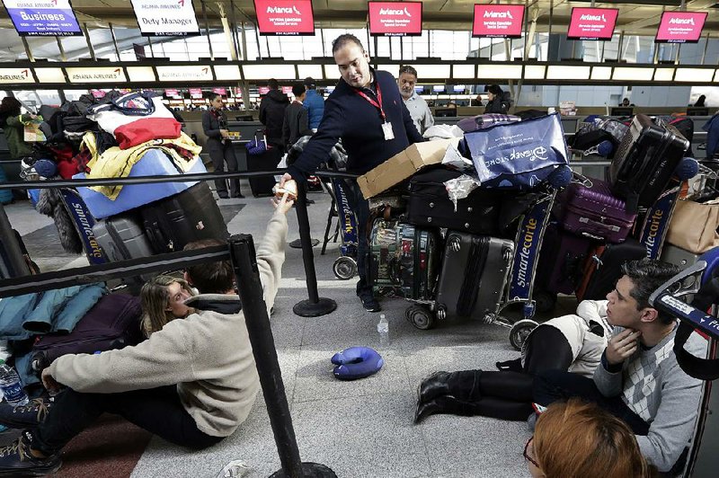 An Avianca employee distributes sandwiches to waiting passengers at New York’s John F. Kennedy Airport Terminal 4 on Monday, a day after a water main broke and flooded the terminal.