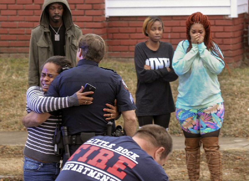 An upset woman is held back by police as firefighters and paramedics try to revive a man fatally shot Monday afternoon in Little Rock. The man was shot at Eastview Terrace Apartments on East 13th and Geyer streets and was then driven a few blocks away to East 15th and College streets, where he was administered CPR by rescue workers.