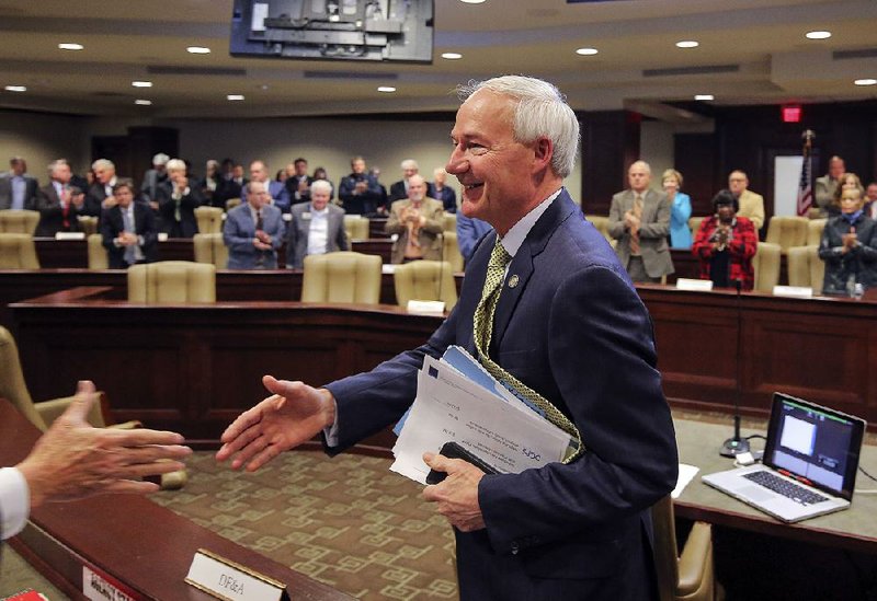 Gov. Asa Hutchinson greets legislators Tuesday at a meeting of the Joint Budget Committee. He said his budget proposal “is conservative in spending, increases our savings and invests in the future.” 