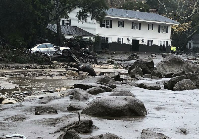 Rocks, mud and debris cover a street in Montecito, Calif., on Tuesday. Marks on the house in the background show how high the mud rose as it swept through the neighborhood. 