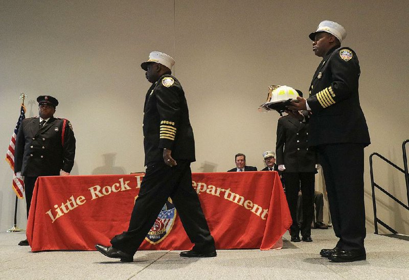 Former Little Rock Fire Chief Gregory Summers walks to the other side of the stage Wednesday after presenting new Fire Chief Delphone Hubbard with a helmet during a change-of-command ceremony. 