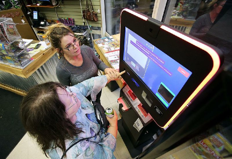 Connie Davis (top) helps Linda Alvis set up a bitcoin account Wednesday at the Corner Store and More in the Simmons Tower in Little Rock.