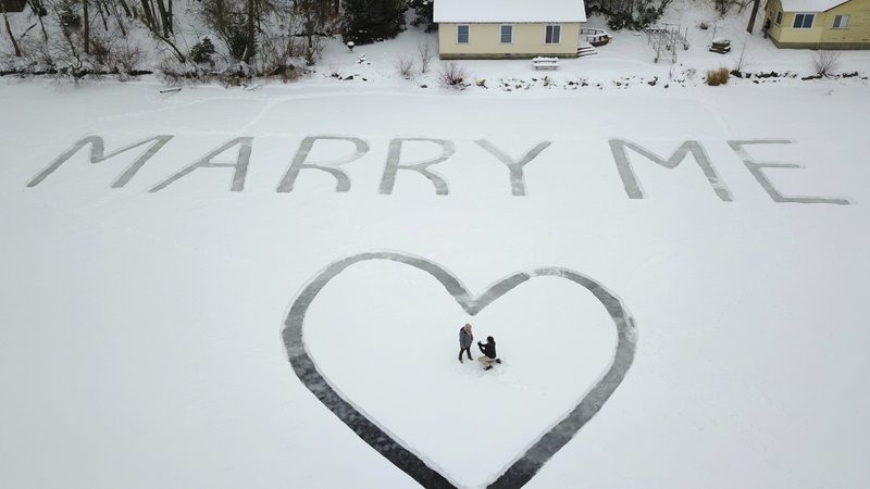 In this Jan. 7, 2018 photo provided by Ed Becker, Gavin Becker and his long-time girlfriend Olivia Toft lay in the snow after he proposed on Eight Crow Wing Lake near Nevis, Minn. Becker had his family's help etching out the big question with a snow blower in 25-foot-tall letters and a huge heart in the snow on the frozen lake. Then Gavin rented a plane and took Toft, who said yes, for a ride over the lake to see where his father took photos of the event. (Ed Becker via AP)

