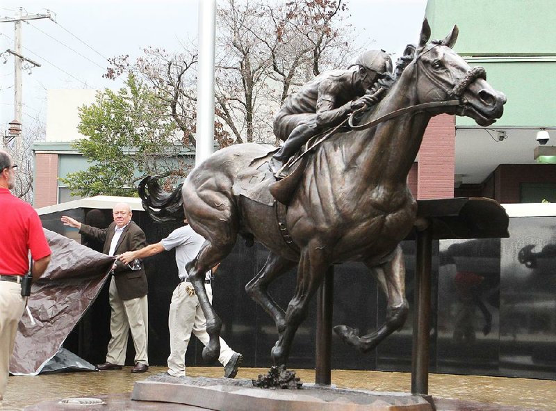 Oaklawn Park employees unveil a bronze sculpture of 2015 Triple Crown winner American Pharoah on Thursday. The statue, designed by James Peniston and commissioned by the late Charles Cella, will greet spectators in front of the grandstand entrance.