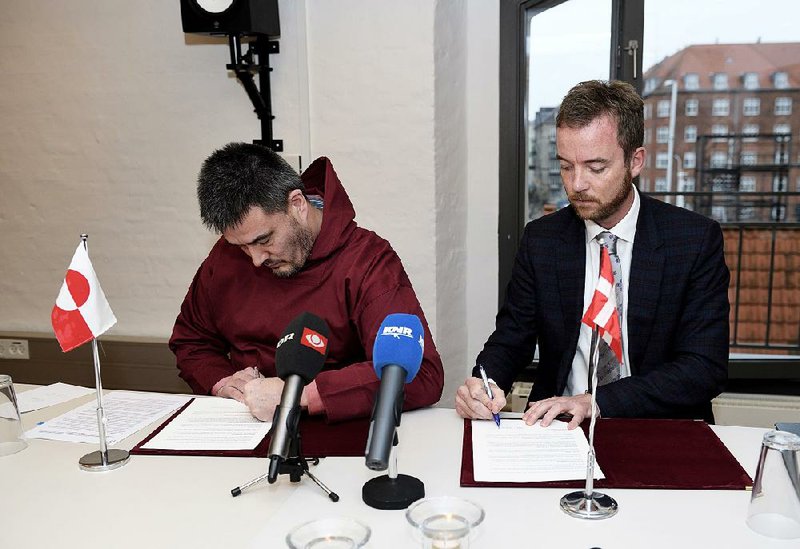 Kim Kielsen (left) of the Greenland government and Denmark’s environment minister, Esben Lunde Larsen, sign an agreement Thursday in Copenhagen on cleaning up rusting U.S. bases in Greenland. 