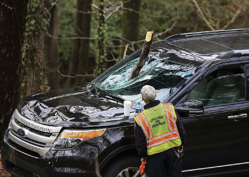 Arkansas Democrat-Gazette/STATON BREIDENTHAL --1/11/18--  A Little Rock firefighter looks at the damage to a car after a tree limb fell through the car's windshield Thursday afternoon on Allsopp Park Road. No one was seriously injured in the incident. 