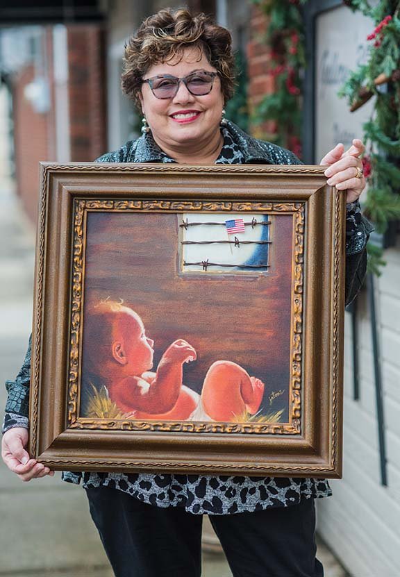 Russellville artist Jeannie Fowler Rodriguez Stone shows her oil painting No Room in America that she will exhibit in the upcoming political art show and performance event in Little Rock. Also a poet, Stone will read some of her own work Friday night.