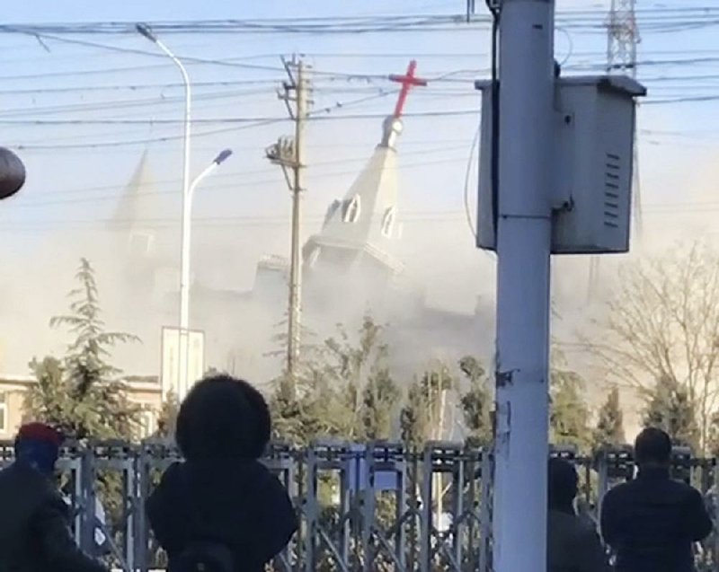 People watch as paramilitary troops use excavators and dynamite to demolish Golden Lampstand Church in Linfen in northern China’s Shanxi province. The church was one of two razed in recent weeks.  