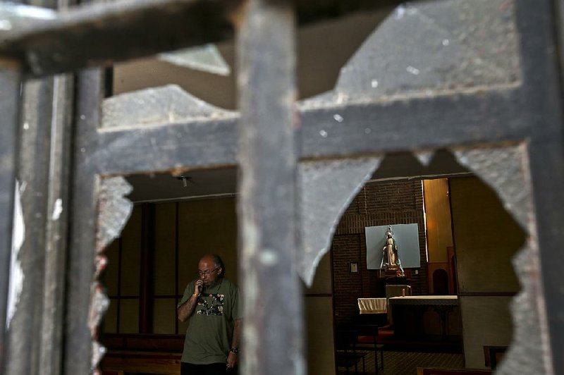 A church employee on Friday surveys the damage at Emmanuel Catholic Church in Santiago, Chile, one of three churches attacked overnight in the city. 