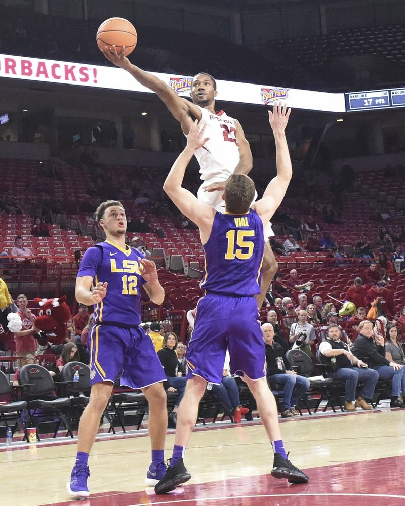 Special to The Sentinel-Record/Craven Whitlow PARTING THE PURPLE SEA: Razorback sophomore guard C.J. Jones (23) from Birmingham, Ala., goes up for two while LSU's Marshall Graves (12) and Reed Vial (15) defend in the Hogs 75-54 loss to LSU at Bud Walton Arena in Fayetteville Wednesday. Jones scored four points in 14 minutes off the bench.