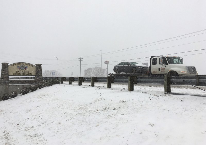 A flatbed tow truck carries a car along a road near Interstate 40 in snow and icy conditions on Friday, Jan. 12, 2018 in Parkers Crossroads, Tenn. (AP Photo/Adrian Sainz)