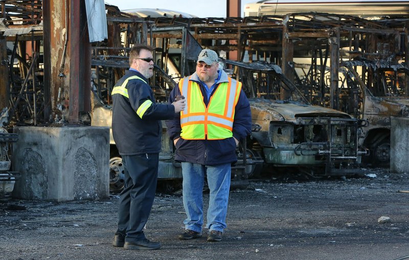 Ozark Regional Transit employees look at the remains of destroyed buses Jan. 10, 2017, in Springdale. Twenty busses were destroyed in the fire.