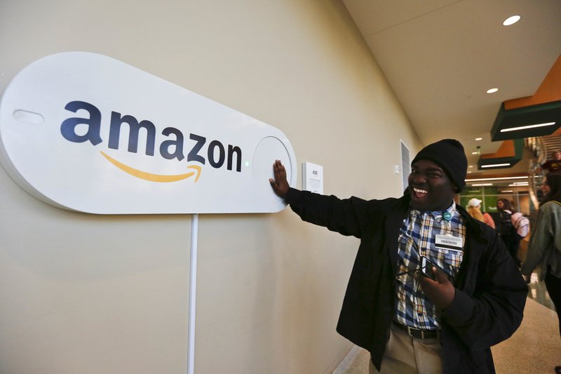 FILE - In this Monday, Oct. 16, 2017, file photo, Zavian Tate, a student at the University of Alabama at Birmingham, pushes a large Amazon Dash button, in Birmingham, Ala. The buttons are part of the city's campaign to lure Amazon's second headquarters to Birmingham. (AP Photo/Brynn Anderson, File)