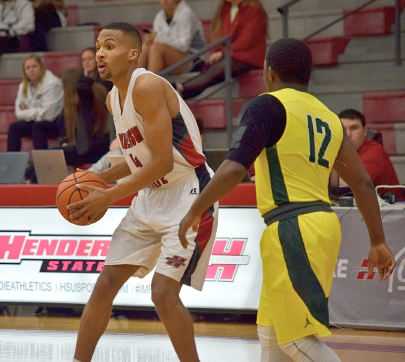 Submitted photo EYES UP: Henderson State senior forward Brad Nairn (23), of Nassau, Bahamas, looks to pass as Arkansas-Monticello senior guard Stephon Gordon adds pressure. The Reddies fell, 82-72, in the road game.