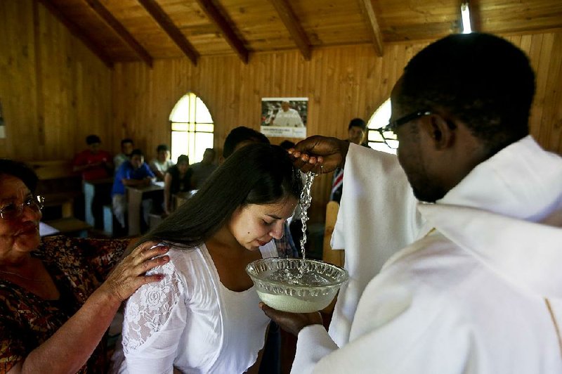 Priest Claude Yves Dilayen baptizes a woman earlier this month in the Mapuche community of Newen Wenu Chau in Temuco, Chile.