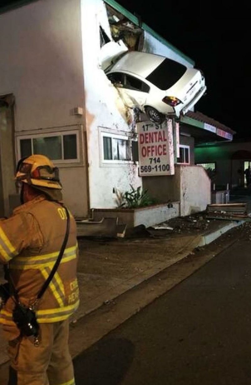 A vehicle that crashed into a building hangs from a second story window in Santa Ana, Calif., in this Sunday photo provided by the Orange County Fire Authority.