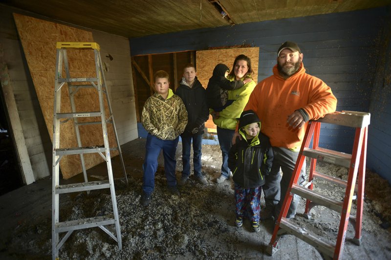 Tim (from right) and Valerie Wright stand Jan. 6 in the bedroom of one of their sons on the second floor of their Cincinnati home with their children, Will Wright, 5; Isaac Wright, 3; Paul Martinez, 12; and Jon Martinez, 10; after a fire heavily damaged their 1930s-era home Christmas Eve. Without insurance, the Wrights are left to repair the house they have been restoring for the last seven years at their own expense with the help of donations from friends and deep discounts from local companies.